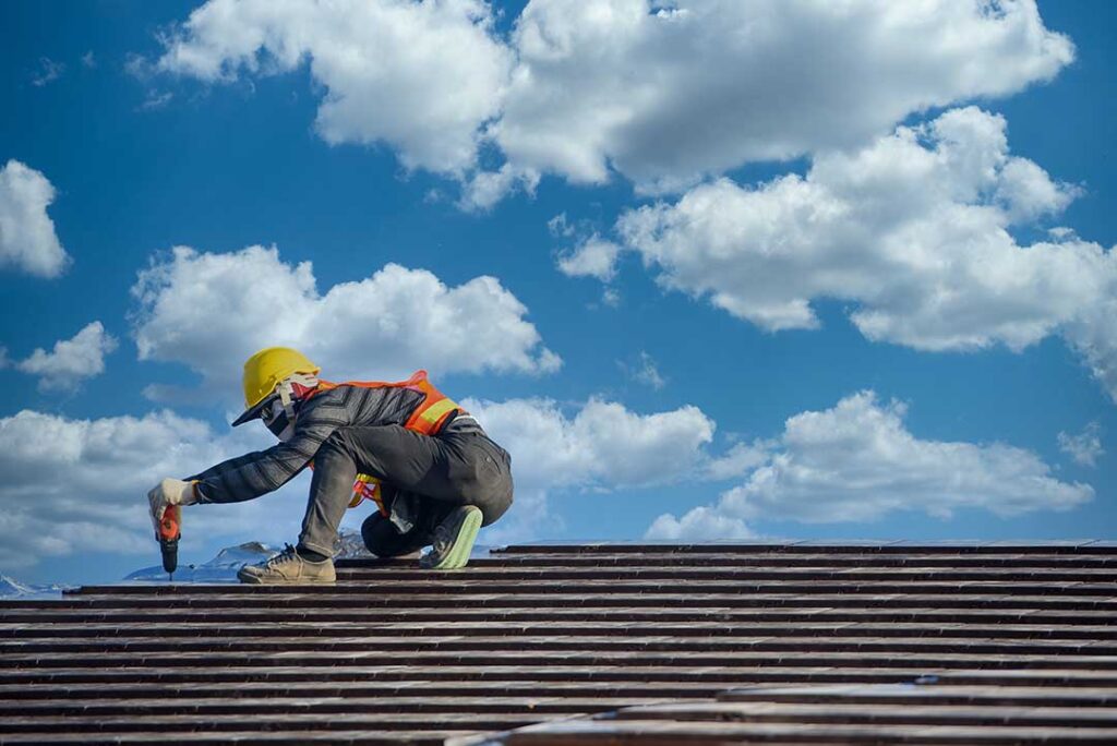 A homeowner examining damaged shingles and water stains on a house roof after heavy rain.