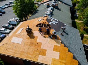 A close-up of attic soffit and ridge vents with daylight filtering through insulation and wooden roof beams.