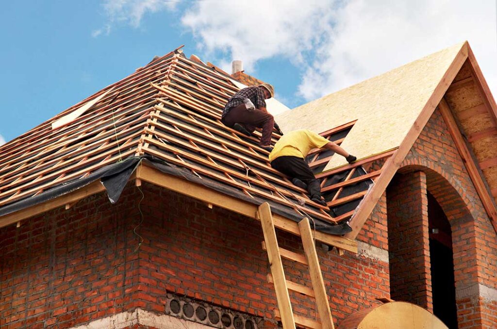 Inspector checking shingles and flashing on a residential roof with a clipboard in hand.