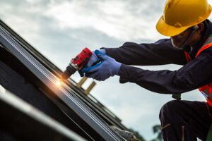 A homeowner uses binoculars to inspect loose shingles while checking water stains inside an attic.
